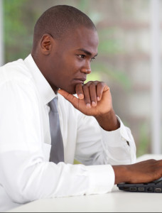 thoughtful african businessman working on laptop